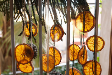 Handmade garland out of dried orange slices, pinecones and evergreen on a glass door shot in...