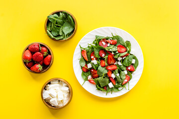 Top view of spinach salad with strawberry and goat cheese