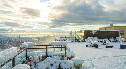 Panoramic winter view  across valley from snowed-in rooftop patio with snow-capped firs in...