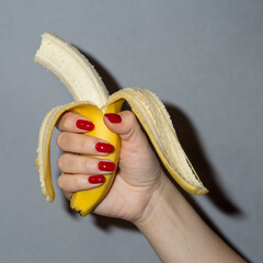 hand with red nails holds a banana