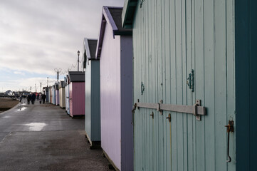 Beach huts along the sea front in the British resort town of Felixstowe. Unrecognisable people walk along the promenade on a dull winter's day.