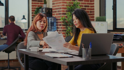 Obraz premium Team of asian women brainstorming strategy ideas in office, starting partnership to help with company growth. Colleagues working with financial statistics and paperwork for development.