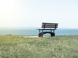 Bench on green grass, water and sky scenery