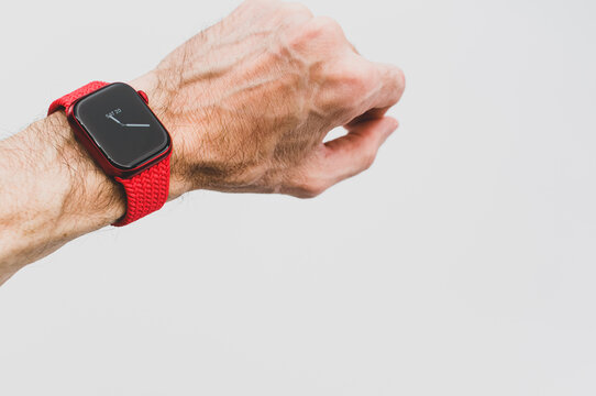 INVERIGO, ITALY - Nov 20, 2021: Man Wrist Wearing Apple Watch Product Red And Charger On A White Background