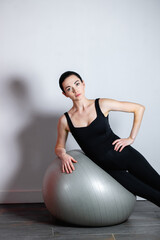 Sporty woman doing pilates toning exercise with the ball