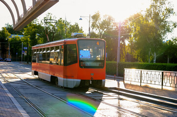 Plakat orange tram on the city street on a sunny day near the platform 