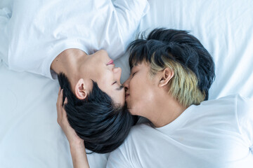 Asian attractive gay kiss boyfriend's forehead to wake up from sleep. 