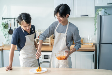 Asian young LGBTQ male gay family enjoy cook foods in kitchen at home. 