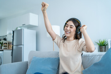 Asian funny woman listen to music and dance on floor in living room.