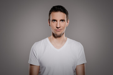 Obraz premium man with an impish grinning on his face while looking at the camera and make a quite smile with his lips