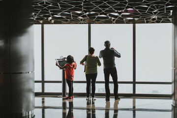 Family using a digital electronic telescope of the Burj Khalifa at the observation deck