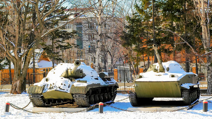 military tanks in the city center against the background of houses in winter in the snow 