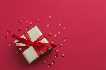 A small gold gift with a red ribbon laying on a red background