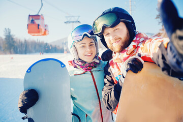 Smiling couple taking selfie together with snowboards background snowy mountain ski resort. Concept...
