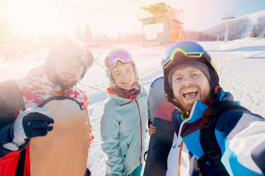 Group of friends skiing and snowboard make selfie photo in winter with sun light on ski resort