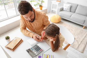 Man helping his little daughter to do lessons at home