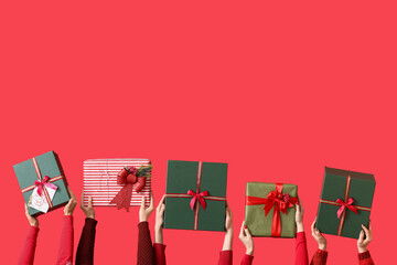 Many hands with Christmas gifts on color background