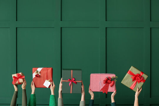 Many hands with Christmas gifts on color background