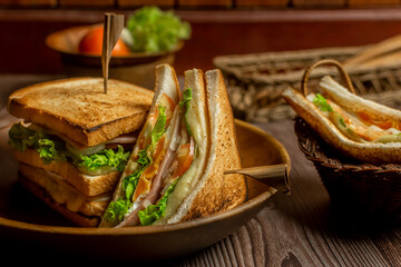 Homemade club sandwich with ham, egg and cheese,tomatoe, lettuce,onion on dark background. Rustic style. Selective Focus. Copy space. 
