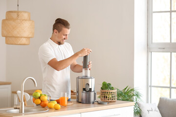 Young man preparing healthy fruit juice in kitchen