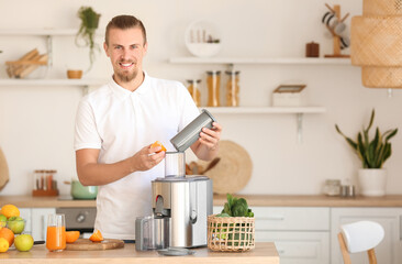 Young man preparing healthy fruit juice in kitchen