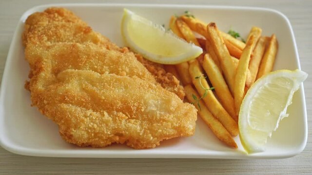 fish and chips - fried fish fillet with potatoes chips and lemon on white plate