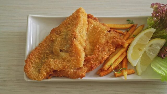 fish and chips - fried fish fillet with potatoes chips and lemon on white plate
