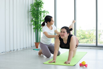 Two Asian woman watching and learning yoga exercising online on computer notebook laptop at home ,concept activity and relax at home