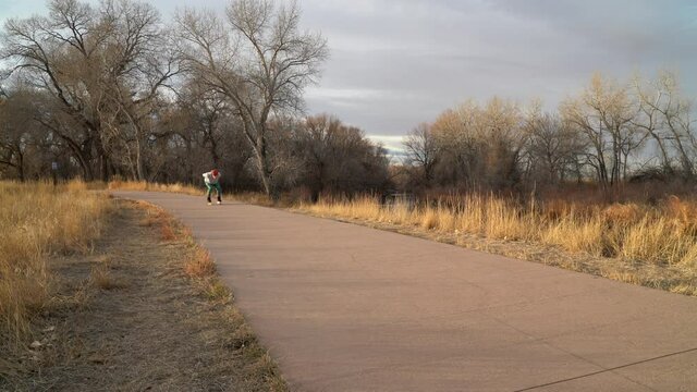 Recreational senior male inline skater in going downhill on a paved bike trail along Poudre River in Fort Collins, Colorado, fall or winter sunset scenery