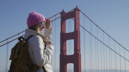 Portrait of happy hipster woman looking on Golden Gate bridge on sunny day outdoors. Closeup cheerful girl with backpack in urban background. Smiling lady outside, San Francisco California USA travel