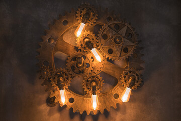 Steampunk architectural style design element of interior.Lamp bulbs fixed on iron industrial gear cogwheels sprocket lighting illuminated equipment
