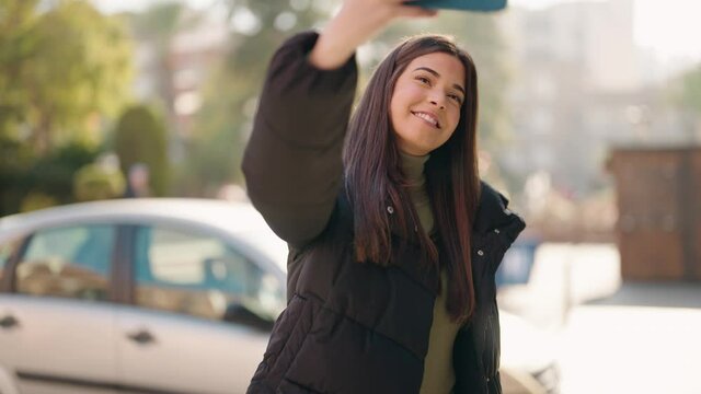 Young hispanic woman smiling confident make selfie by the smartphone at street