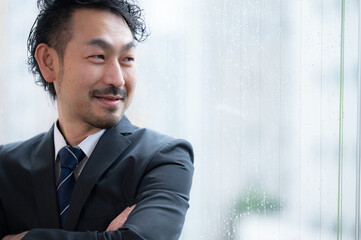 会社の未来を考えるハンサムなスーツのアジア系経営者風のヒゲ男性...