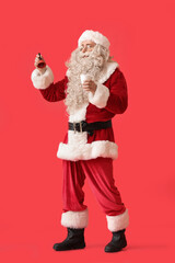 Santa Claus with glass of milk and Christmas bell on red background