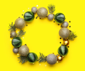 Frame made of Christmas balls, fir branches and confetti on yellow background