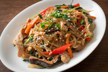 japchae or stir-fried Korean vermicelli noodles with vegetables and pork topped with white sesame