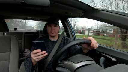 Irresponsible driver potentially breaking the law by texting on his phone whilst driving.