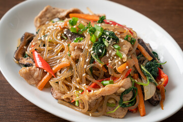 japchae or stir-fried Korean vermicelli noodles with vegetables and pork topped with white sesame