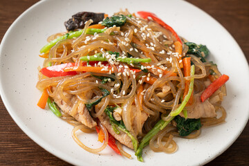 japchae or stir-fried Korean vermicelli noodles with vegetables and pork topped with white sesame