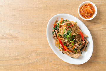 japchae or stir-fried Korean vermicelli noodles with vegetables and pork topped with white sesame