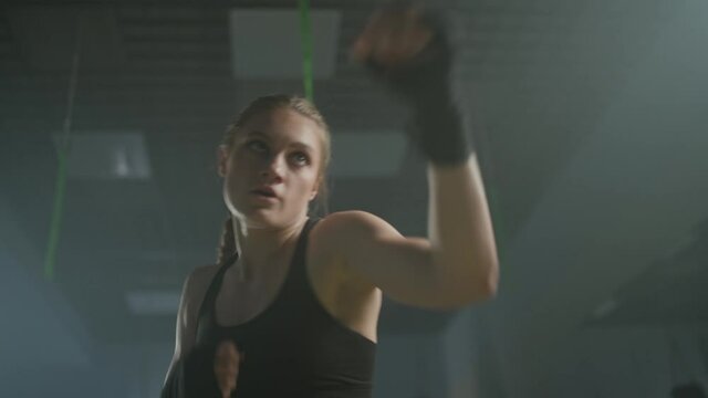 Woman power, young female fighter trains his punches, training in the boxing gym, female trains a series of punches fast, handheld.