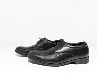 A pair of formal black shoes with laces displayed with white background
