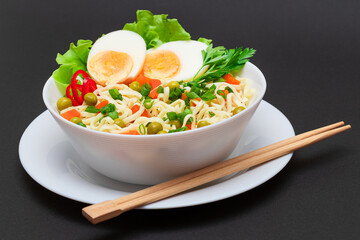 Beautiful Noodle Dish with Green Pea, Carrot, Eggs, Red Hot Pepper and Greens on Black Background. Instant Noodles with Vegetables