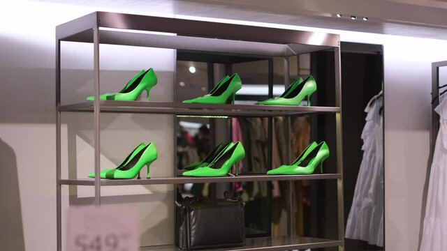 Elegant stylish trendy lime green high heels shoes in a row on the metallic showcase in luxury fashion retail store in the shopping mall