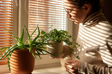 Woman standing at the window with flowerpot