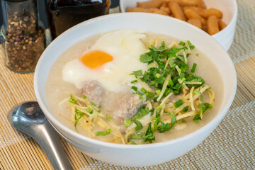Porridge rice gruel with egg in white bowl Chinese Traditional breakfast with deep-fried dough stick.