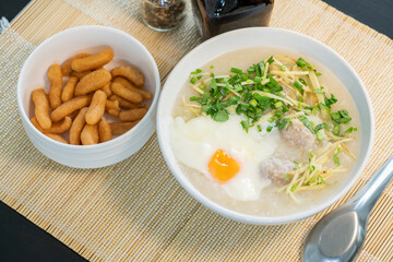 Porridge rice gruel with egg in white bowl Chinese Traditional breakfast with deep-fried dough stick.