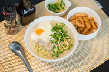 Porridge rice gruel with egg in white bowl Chinese Traditional breakfast with deep-fried dough stick.