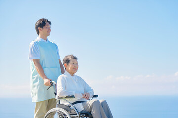 介護士と車椅子に乗る高齢者　屋外