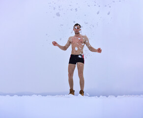 Naked man in the snow. Healthy cold swim. Winter fun, tempering procedures. Guy snow showers for...